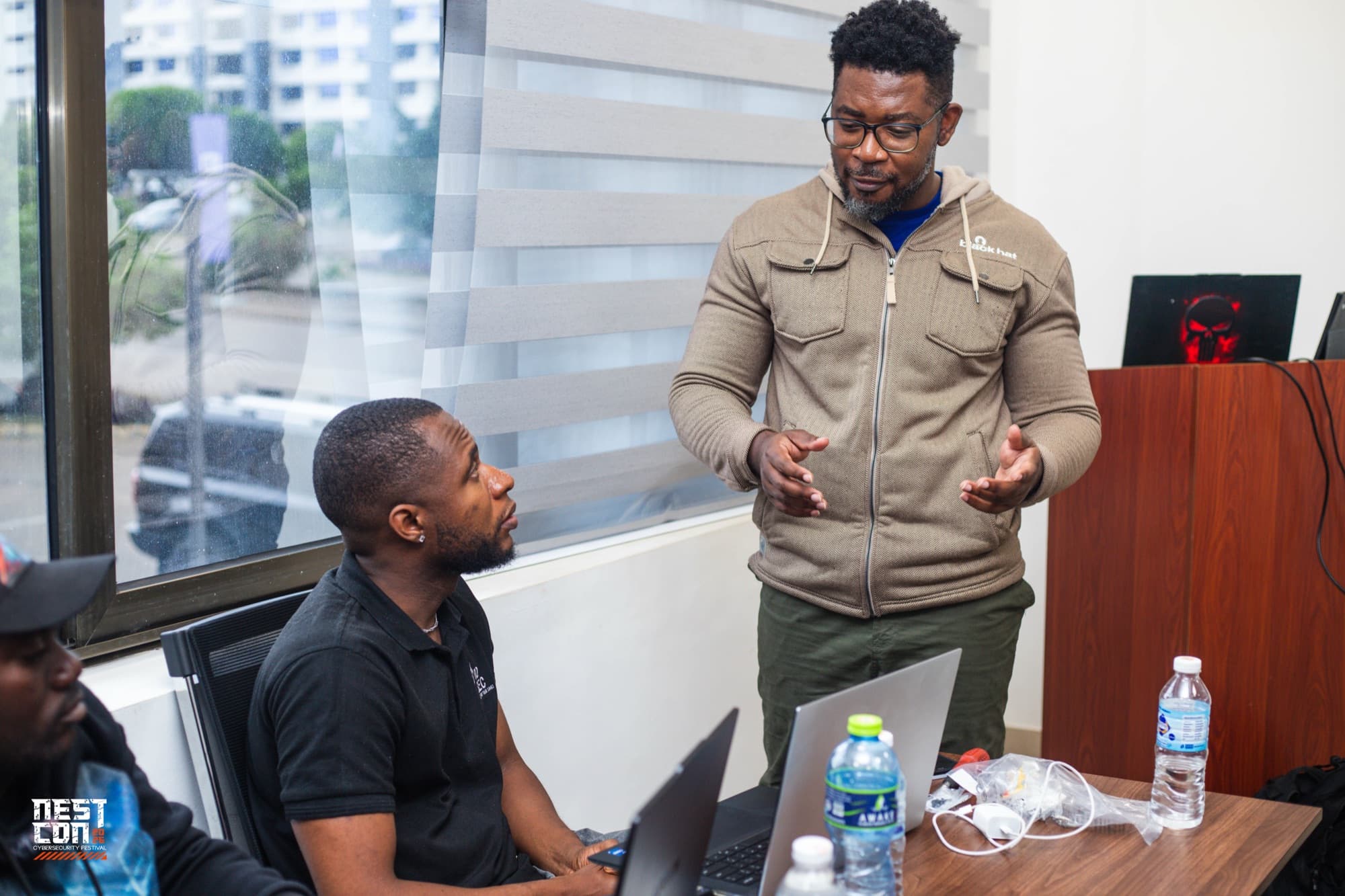 Two attendees in conversation beside a laptop at a NESTCON event.
