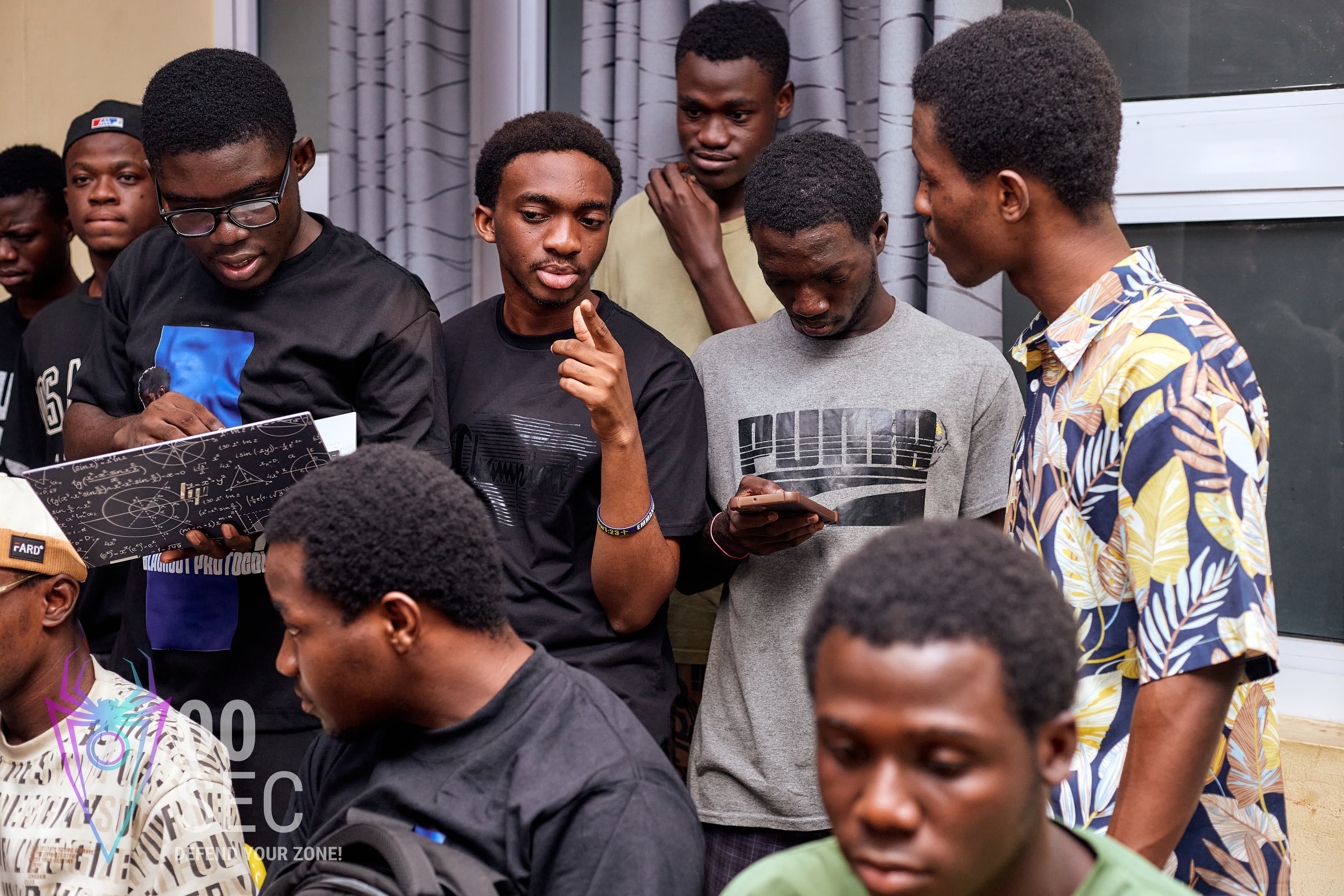 A group of students compare notes on a phone and a notebook of equations.