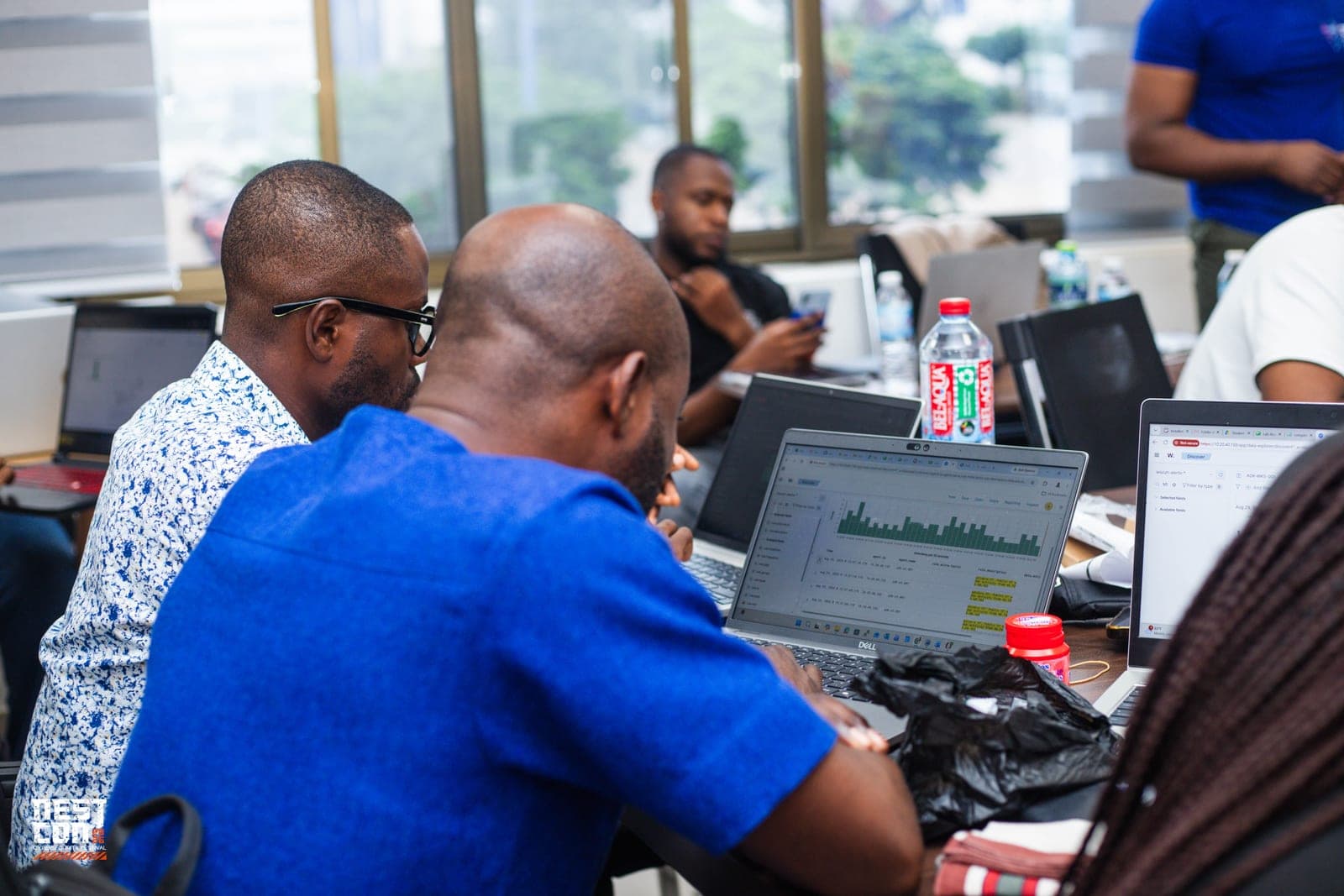 Two attendees reviewing a live security monitoring dashboard together during a workshop.